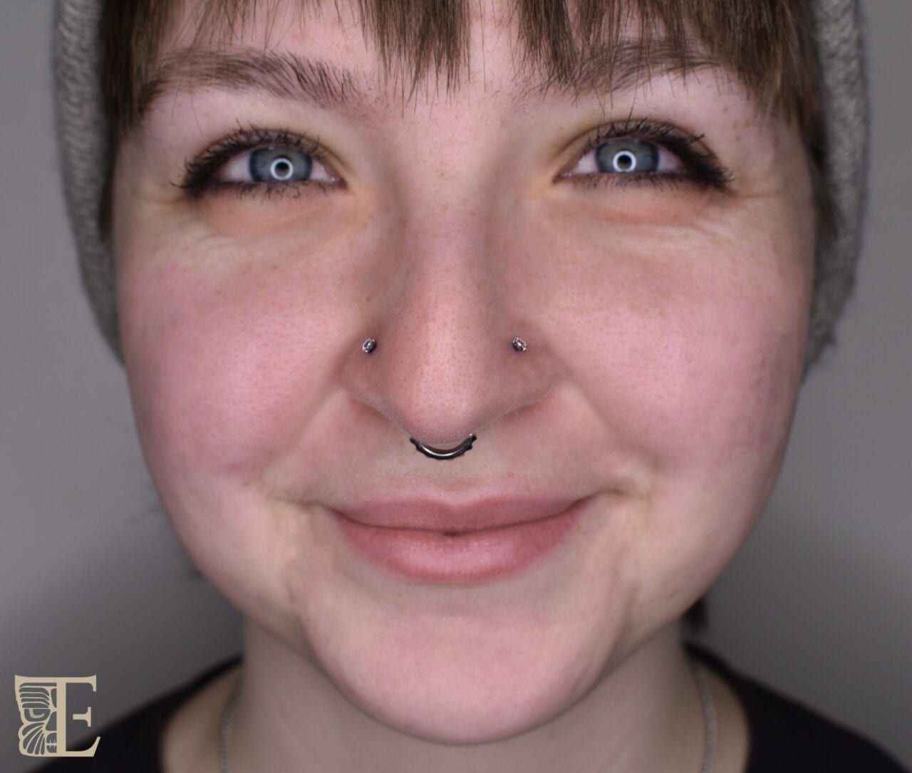 Close-up of a beautiful pair of matching double nostril piercings with small stud jewelry, professionally done at Tribal Expression body piercing studio in Calgary