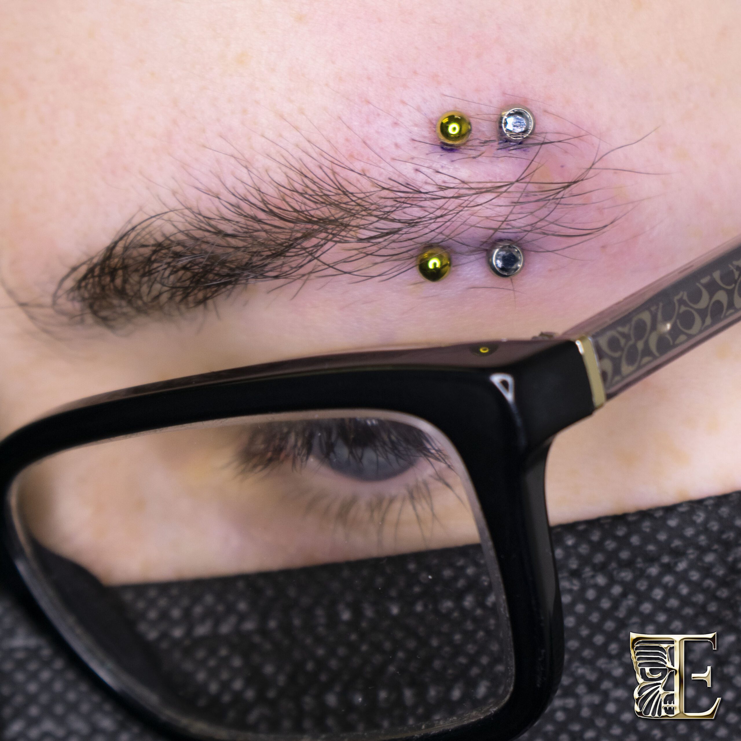 Double Eyebrow Piercings with Anodized Titanium – Custom Jewelry from Tribal Expression Calgary Side profile of a person with two eyebrow piercings using different colors of anodized titanium jewelry, custom made in Calgary and pierced at Tribal Expression professional studio