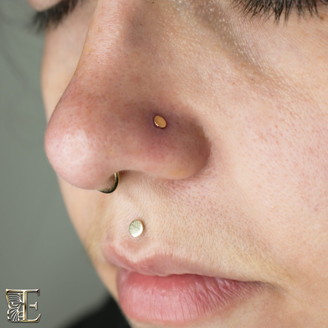 Forward-facing portrait of a beautiful young woman with a philtrum (medusa) piercing, septum piercing, and nostril piercing, all styled with custom jewelry from Tribal Expression in Calgary