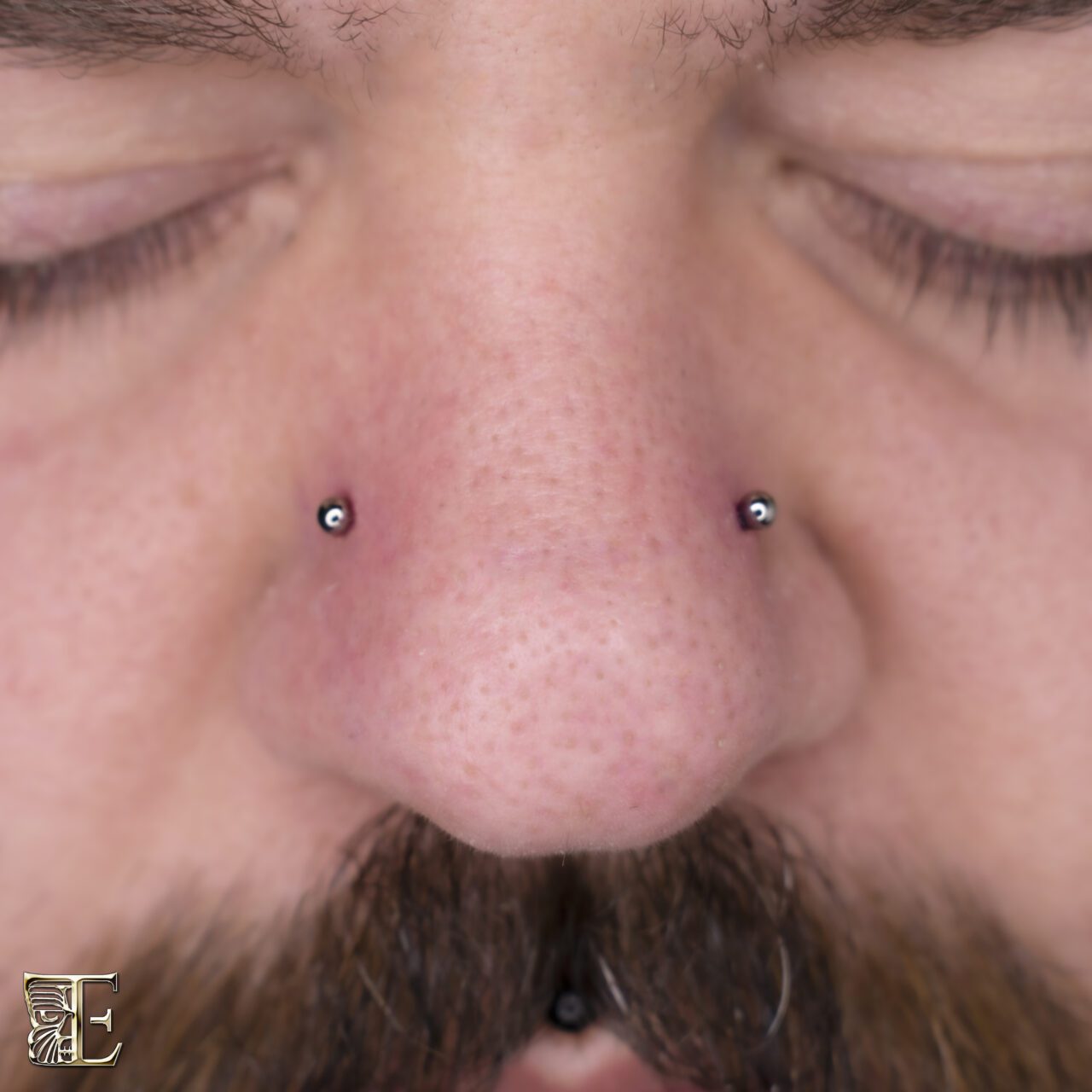 Forward-facing photo of a male with a neatly placed nostril piercing featuring a small titanium nose stud, professionally done at Tribal Expression body piercing studio in Calgary