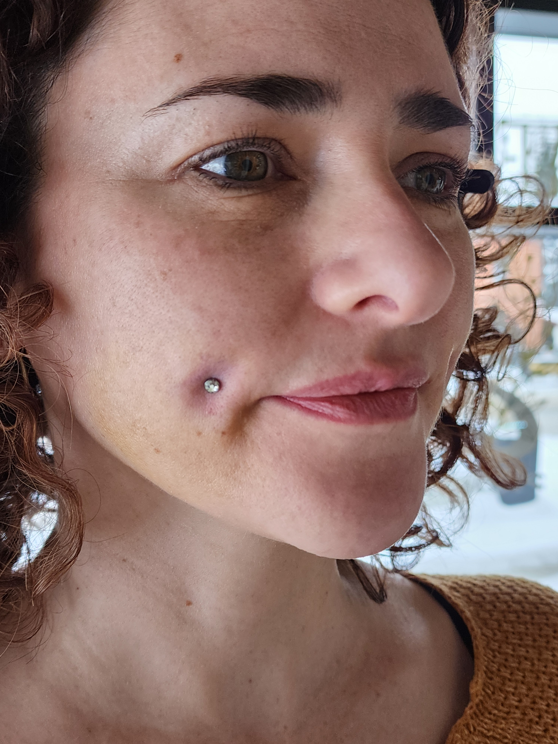 Side-profile close-up of the same client from the cheek piercing series, showcasing symmetrical dimple piercings with high-quality jewelry from Tribal Expression in Calgary, highlighting facial piercing aesthetics and expert placement