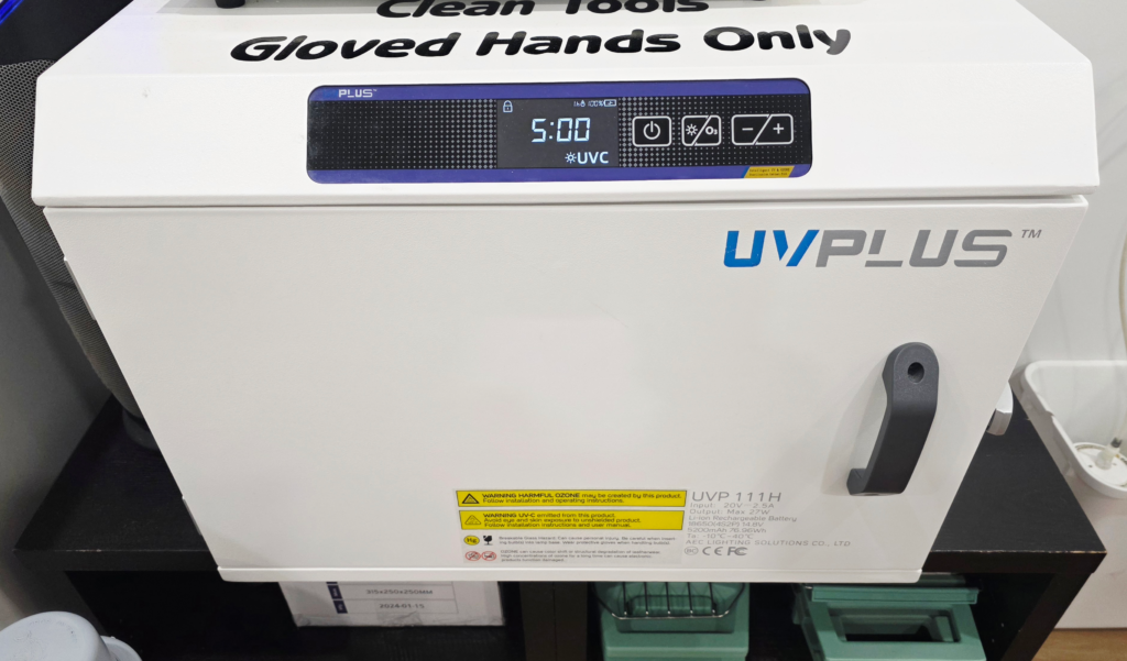 Photo of a unique UV light storage cabinet at Tribal Expression in Calgary, used to keep sterilized piercing instrument packages disinfected and pristine on the outside as well as the inside