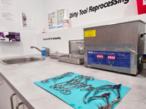 Detailed photo of Tribal Expression’s decontamination area inside the sterilization room in Calgary, showing the dirty side where used piercing instruments are received, rinsed, and ultrasonically cleaned before packaging and autoclave sterilization
